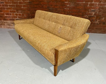 May include: A yellow fabric sofa with wooden legs. The sofa has a tufted back and a textured fabric.
