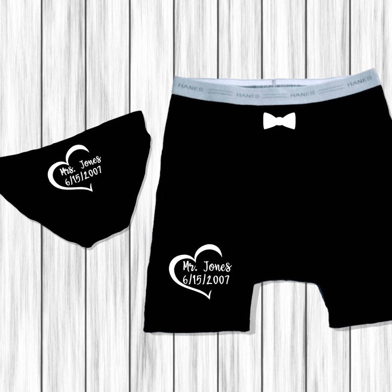 Op de afbeelding: Een zwart-witte afbeelding van een paar ondergoed en een paar boxershorts. Het ondergoed heeft een wit hart met de tekst "Mrs. Jones 6/15/2007" erop. De boxershorts hebben een wit hart met de tekst "Mr. Jones 6/15/2007" erop.