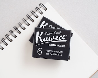 Könnte beinhalten: Eine schwarze Tintenpatronen-Verpackung für einen Füllfederhalter. Die Verpackung trägt die Aufschrift "Pearl Black Kaweco" und "Germany, Since 1883." Außerdem steht "Tintenpatronen Ink Cartridges" darauf und die Nummer "6".