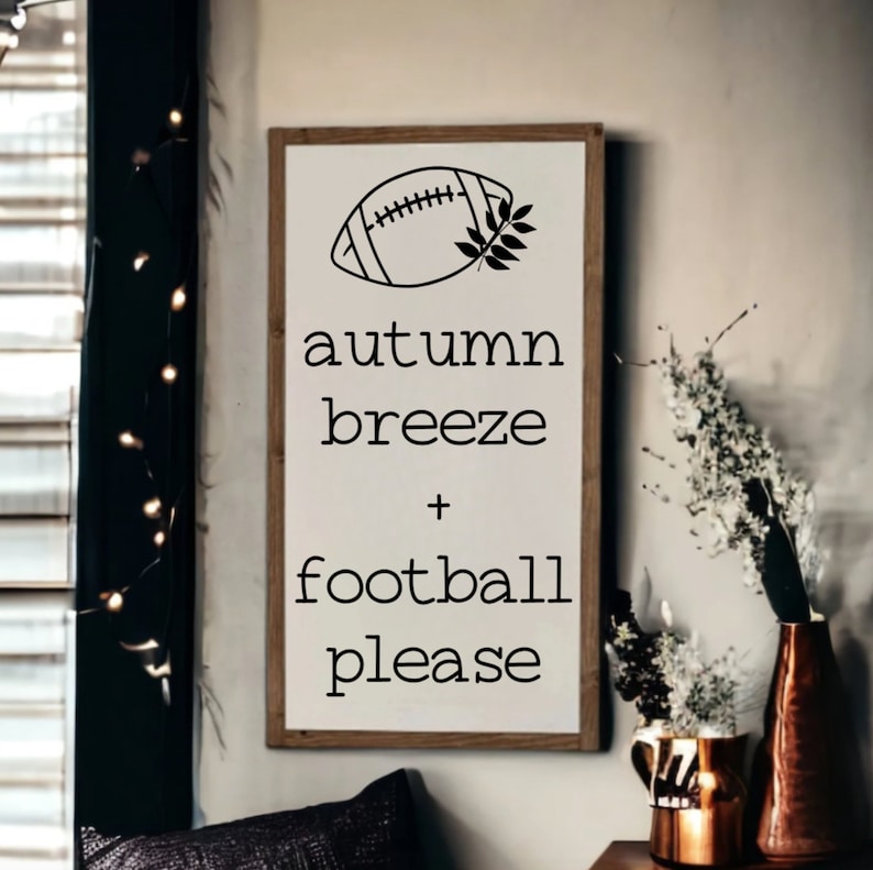 K&ouml;nnte beinhalten: Ein wei&szlig;es Holzschild mit schwarzem Text und einer Fu&szlig;ballabbildung. Der Text lautet "Herbstbrise + Fu&szlig;ball bitte".