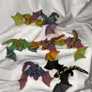 May include: A collection of colorful dragon figurines. The dragons feature a variety of colors, including green, yellow, orange, purple, and black. Each dragon has detailed wings and a unique design, perfect for fantasy enthusiasts.