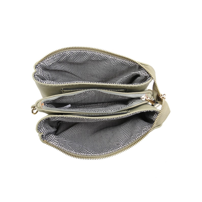 Puede incluir: Un bolso bandolera de color verde claro con tres compartimentos separados con cremallera. El bolso est&aacute; abierto y el forro es de un patr&oacute;n de espiga en blanco y negro.