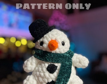 May include: A white crocheted snowman with a black top hat, green scarf, and black button eyes. The snowman is holding a carrot nose.