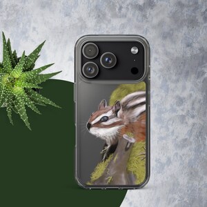 May include: Clear phone case featuring a detailed illustration of a chipmunk. The chipmunk has brown and white fur and is perched on a mossy branch. The case has a clear border and a dark gray background.