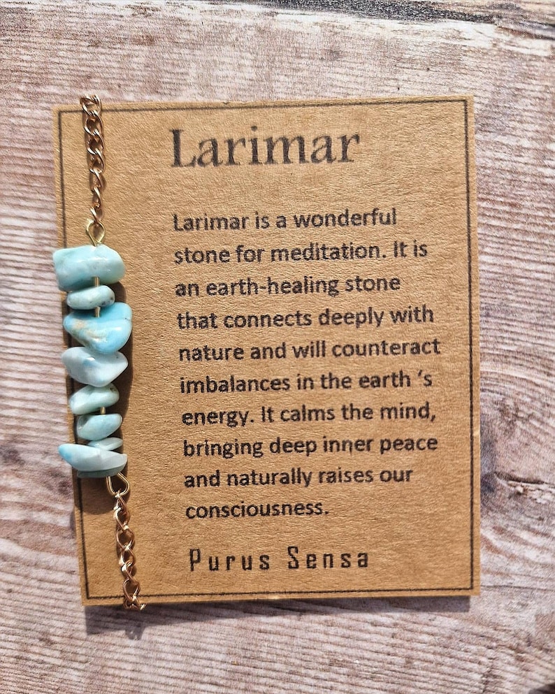 May include: A gold chain necklace with light blue Larimar beads. The card reads "Larimar is a wonderful stone for meditation. It is an earth-healing stone that connects deeply with nature and will counteract imbalances in the earth's energy. It calms the mind, bringing deep inner peace and naturally raises our consciousness. Purus Sensa"
