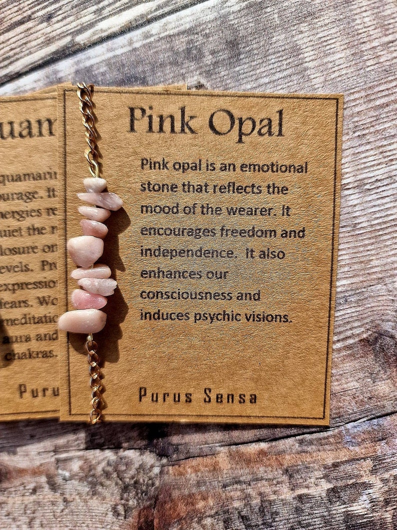 May include: Pink Opal crystal bracelet with gold chain and a brown card with the text "Pink Opal" and information about the stone's properties. The card also includes the text "Purus Sensa".