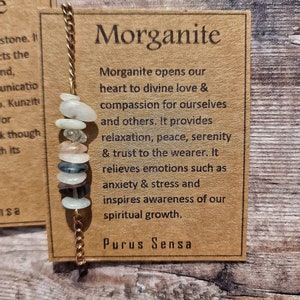 May include: A brown card with the text "Morganite" in large letters. The card describes the properties of the Morganite gemstone, including its ability to open the heart to divine love, provide compassion, and promote relaxation, peace, and serenity. The card also mentions that Morganite relieves emotions such as anxiety and stress and inspires awareness of spiritual growth. The text "Purus Sensa" is printed at the bottom of the card.