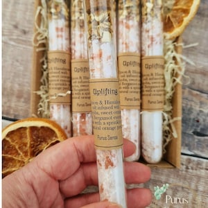 Pu&ograve; includere: Un set di sei provette di vetro riempite con sali da bagno. Le provette sono etichettate "Uplifting" e contengono sale dell'Himalaya infuso con arancia dolce, bergamotto e ylang ylang. Le provette sono disposte in una scatola di legno con una scorza d'arancia naturale.