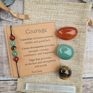 May include: Courage crystal kit with carnelian, green aventurine, tiger eye, and clear quartz crystals. The kit includes a card with information about the crystals and their properties.  The card reads: "Courage. Carnelian increases passion, vitality and good luck. Green Aventurine provides strength, courage, confidence, and happiness. Tiger Eye provides protection and strengthens self-worth. Purus Sensa."