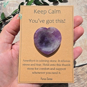 May include: A heart-shaped amethyst stone on a card with the text "Keep Calm You've got this!". The card also states that amethyst is a calming stone. The stone is purple and white.