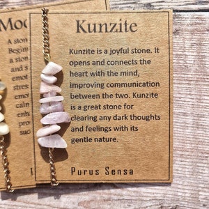 May include: A pink Kunzite crystal necklace with a gold chain. The card reads "Kunzite is a joyful stone. It opens and connects the heart with the mind, improving communication between the two. Kunzite is a great stone for clearing any dark thoughts and feelings with its gentle nature."  The card also reads "Purus Sensa".