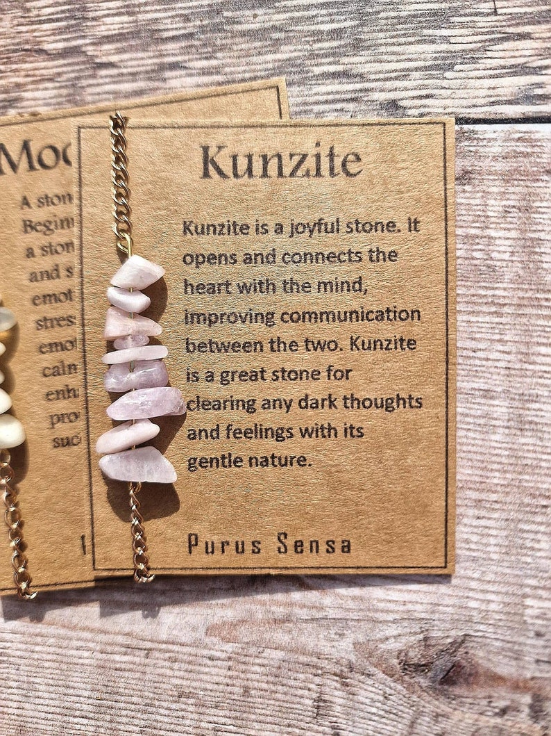 May include: A pink Kunzite crystal necklace with a gold chain. The card reads "Kunzite is a joyful stone. It opens and connects the heart with the mind, improving communication between the two. Kunzite is a great stone for clearing any dark thoughts and feelings with its gentle nature."  The card also reads "Purus Sensa".