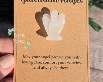 Può includere: Una statuetta di angelo di cristallo bianco su una carta marrone con il testo "Guardian Angel" e "May your angel protect you with loving care, comfort your worries, and always be there." La carta ha anche il testo "Purus Sensa" in alto e in basso.