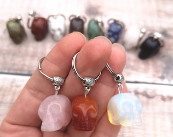 May include: Three crystal skull keychains with silver rings. The skulls are carved from rose quartz, carnelian, and opal.