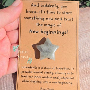 May include: A brown card with the text "And suddenly, you know...It's time to start something new and trust the magic of New beginnings!" and a quote about labradorite, a stone of transition. The card has a small, light green star-shaped stone attached to it.