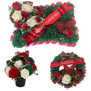 Puede incluir: Un arreglo floral rectangular, una maceta redonda y una corona circular, todos con follaje verde oscuro, rosas rojas y blancas, bayas rojas, mariposas rojas con purpurina y cintas rojas con el texto MERRY CHRISTMAS o THINKING OF YOU AT CHRISTMAS TIME.