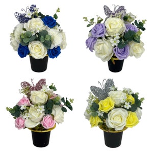 Könnte beinhalten: Vier Blumenarrangements in schwarzen Töpfen mit goldenen Rändern. Jedes Arrangement zeigt Rosen und andere Blumen in verschiedenen Farben, darunter Blau, Lila, Rosa und Gelb. Dekorative Schmetterlingsakzente sind enthalten.