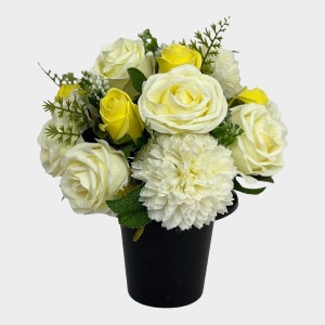 Peut inclure: Un arrangement de fleurs artificielles blanches et jaunes dans un pot noir. L'arrangement comprend des roses et des œillets.