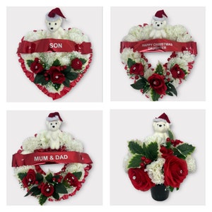 Op de afbeelding: Vier kerstbloemstukken met witte anjers, rode rozen en groene bladeren. Elk stuk heeft een kleine teddybeer met een kerstmuts en een rood lint met tekst. De arrangementen zijn in verschillende vormen.
