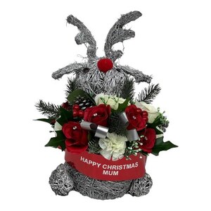 May include: A silver wire reindeer Christmas decoration with a red nose and antlers. The reindeer holds a bouquet of red and white roses, greenery, and a red banner that reads "Happy Christmas Mum."