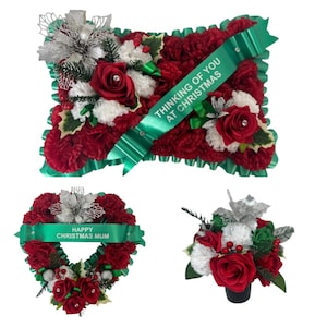 Könnte beinhalten: Weihnachtliche Blumengestecke in Rot, Weiß und Grün. Das Bild zeigt ein Blumenkissen mit dem Text "Thinking of You at Christmas" auf einem grünen Band. Ein herzförmiger Kranz mit "Happy Christmas Mum" und ein kleiner Strauß sind ebenfalls zu sehen.