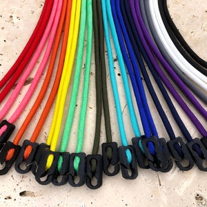 May include: A variety of colorful paracord lanyards with black plastic clasps. The lanyards are arranged in a rainbow pattern.