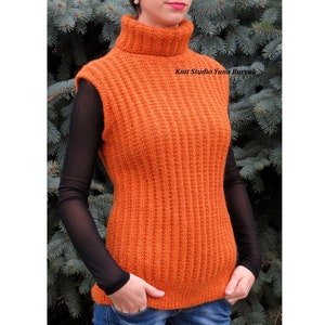 Puede incluir: Un suéter sin mangas naranja con cuello alto y diseño de punto acanalado. El suéter tiene un cuello alto y una silueta ajustada. El texto "Knit Studio Yana Buryak" es visible. La modelo lleva una camisa negra de manga larga debajo.