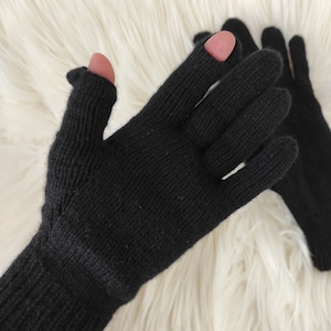 May include: A pair of black fingerless gloves with a long cuff. The gloves are made of a soft, knitted fabric.