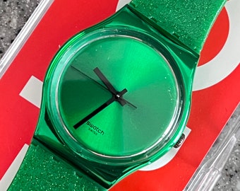 Swatch watch NEW never worn in box with battery plastic still on face battery included black accent hands and glitter green accents GG213