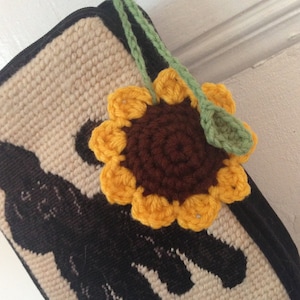 Peut inclure: Un sac en crochet beige avec une silhouette noire de chat et un tournesol en crochet jaune avec un centre brun.