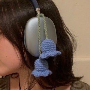 May include: Blue headphones with a light blue crocheted flower charm attached to the cord.