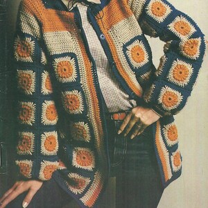 May include: A crocheted cardigan with a geometric pattern in shades of orange, blue, and beige. The cardigan has a button closure and long sleeves.