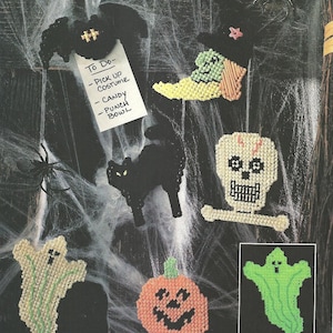 May include: A collection of plastic canvas Halloween decorations including a black bat holding a To Do list, a witch hat and boot, a black cat, a skull, a ghost, a pumpkin, and a green ghost. The list reads: To Do- Pick Up Costume, Candy, Punch Bowl.