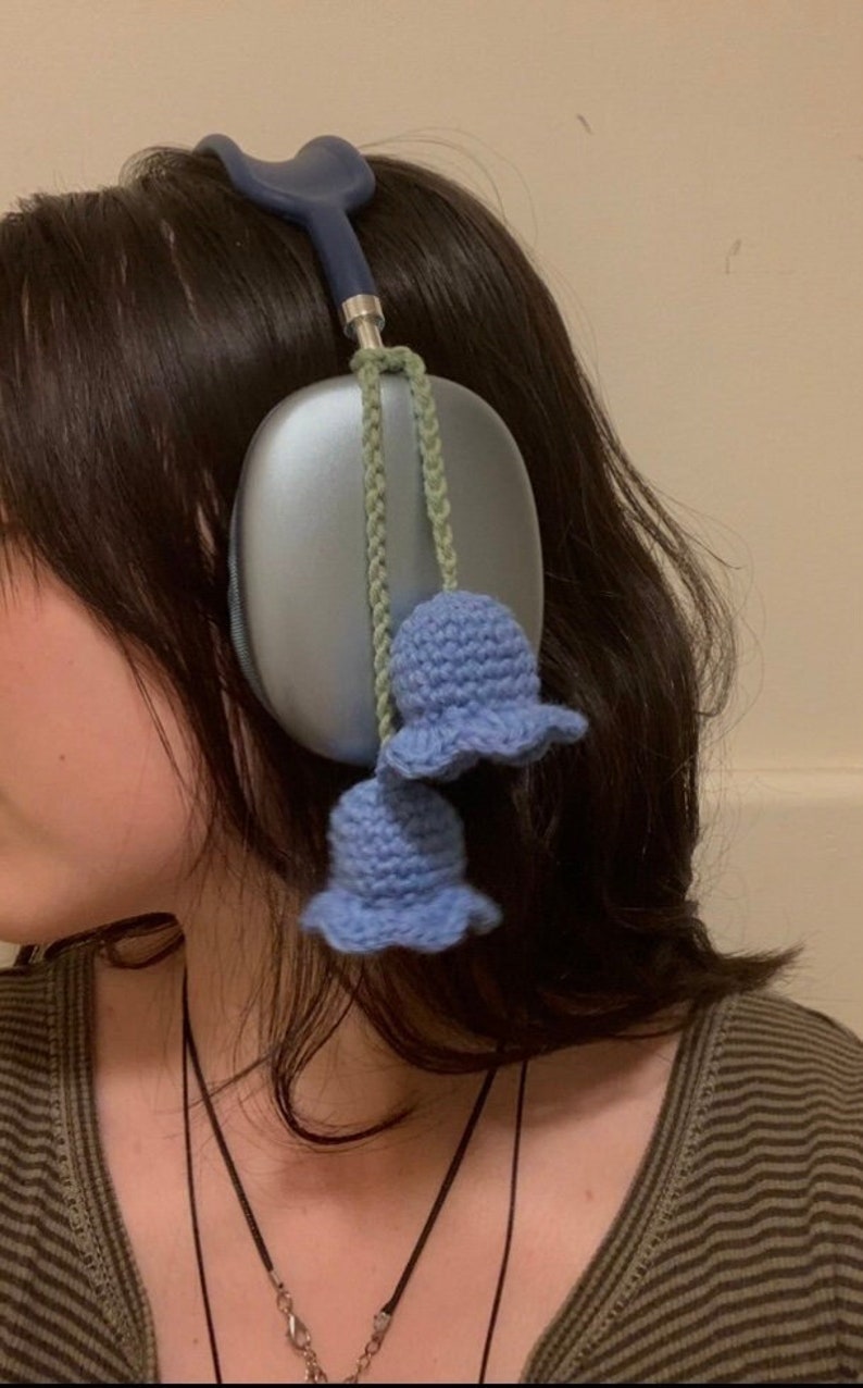May include: Blue headphones with a light blue crocheted flower charm attached to the cord.
