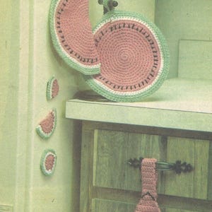 May include: A set of crocheted kitchen accessories featuring a watermelon theme, including a round potholder, a crescent-shaped piece, three small circular accents, and a hanging towel with a pink, white, and green yarn pattern.