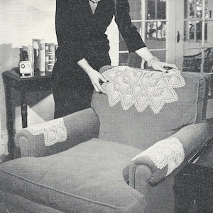 Puede incluir: Imagen en escala de grises de un sillón vintage con detalles de encaje decorativo. La silla tiene una tela de color claro con tapetes de encaje blanco en el respaldo y los reposabrazos. Una persona sostiene el tapete de encaje en el respaldo.