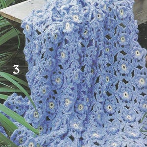 May include: A crocheted blanket with a blue and white floral pattern. The blanket is made with a delicate stitch and has a soft, airy feel.
