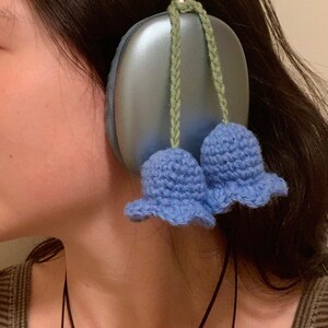 May include: Blue headphones with a light blue crocheted flower charm attached to each earcup.