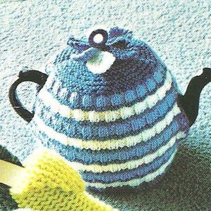 Puede incluir: Un calentador de tetera tejido con rayas azules y blancas. El calentador tiene un asa y un pico negros. Un pequeño objeto tejido amarillo es visible en primer plano. Ideal para mantener el té caliente.