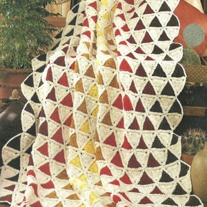 May include: A crocheted throw blanket with a geometric pattern of triangles in shades of red, brown, yellow, and white.