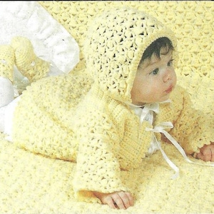 May include: A baby wearing a handmade, light yellow crochet outfit, including a hooded jacket and matching booties. The jacket has a white ribbon tie closure. The baby is lying on a matching yellow crochet blanket.