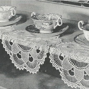 Puede incluir: Tres tazas de té de porcelana blanca con motivos florales y platillos a juego, cada una sobre un tapete de ganchillo blanco circular con borde festoneado. Las tazas tienen dos pequeñas asas y están dispuestas en fila sobre una superficie.
