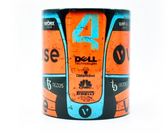 May include: A white ceramic mug with a black, orange, and blue design. The mug features a racing car number "4" with sponsors' logos, including Dell Technologies, DataRobot, CNBC, and Tezos.