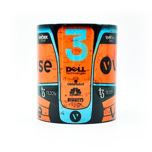 May include: Orange and blue ceramic mug with a racing car design. The mug features the number "3" and logos for Dell Technologies, DataRobot, CNBC, and Pirelli.