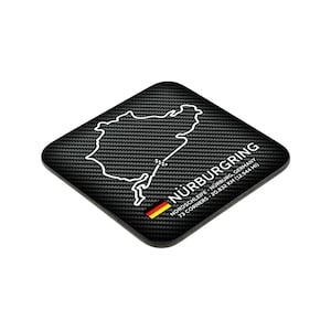 Peut inclure: Sous-verre carré noir avec un contour blanc du circuit de course du Nürburgring. Le sous-verre a un motif en fibre de carbone et le texte "Nürburgring, Nordschleife - Nürburg, Allemagne, 73 virages - 20,832 km (12,944 mi)".