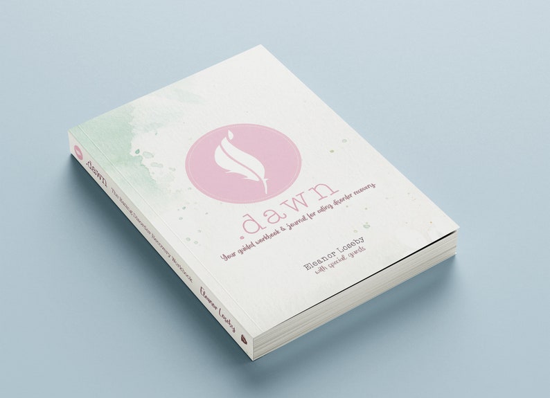 May include: A white book with a pink circle on the cover. The circle contains a white feather design. The book title is "dawn" and the text reads "Your guided workbook & journal for finding inner harmony". The author is Eleanor Loseby with special guests.