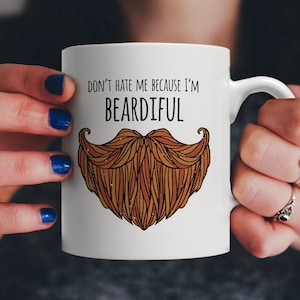 Puede incluir: Taza de cerámica blanca con un diseño de barba marrón y el texto "No me odies porque soy barbudo".