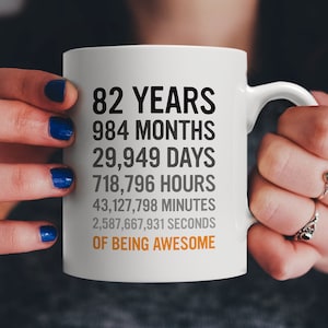 May include: White ceramic mug with black text that reads "82 Years, 984 Months, 29,949 Days, 718,796 Hours, 43,127,798 Minutes, 2,587,667,931 Seconds of Being Awesome".
