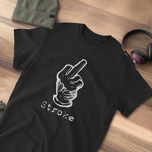 May include: Black t-shirt with a white graphic of a hand giving the middle finger and the word "stroke" underneath.