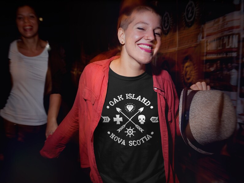 May include: A black t-shirt with a white graphic design featuring the text "Oak Island, Nova Scotia" and a compass, skull, cross, and diamond.